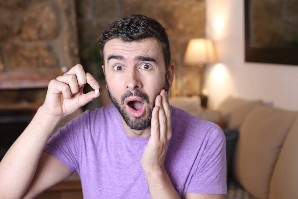 Man holds a tooth that he lost - he should not postpone replacing it with a dental implant.